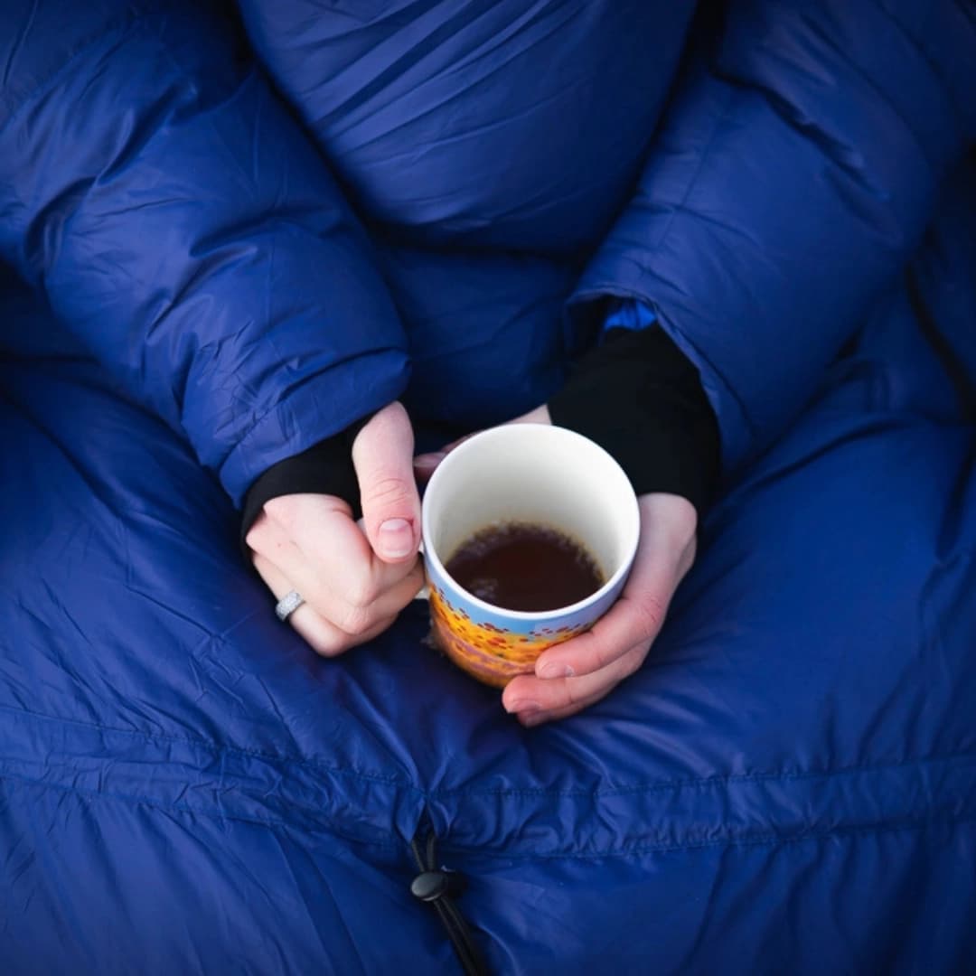 En person med en kaffekopp utenfor en bobil en kjølig høstmorgen.