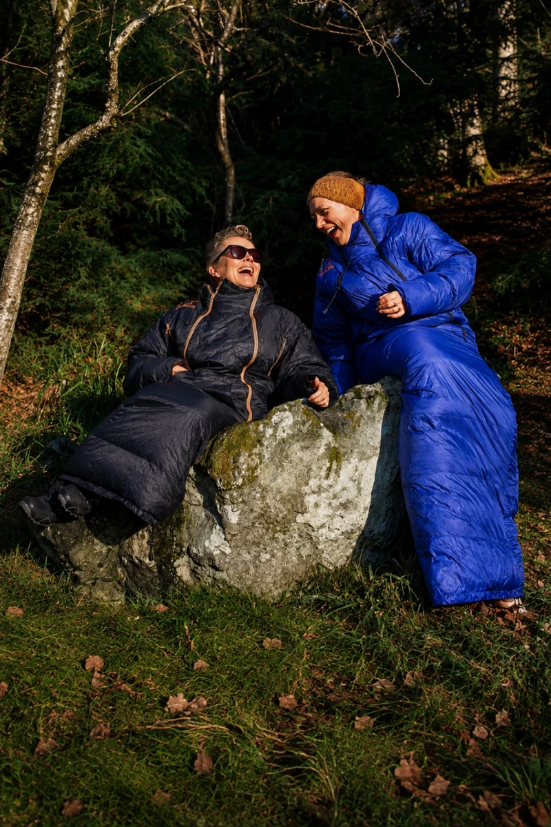 To kvinner i Utekos Mikrofiber sitter på en stein i skogen.