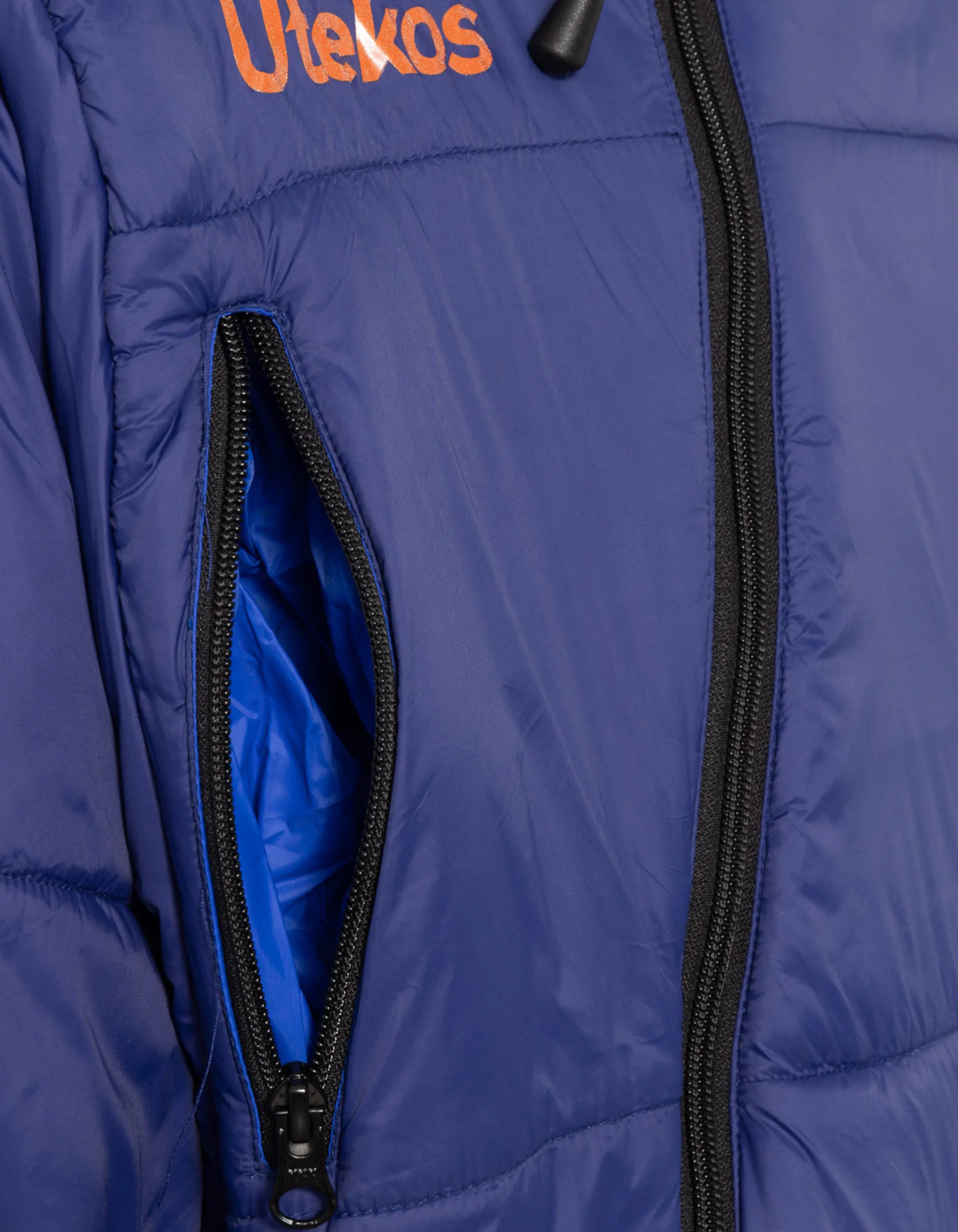 Nærbilde av lomme og glidelås på fjellblå Utekos Mikrofiber.