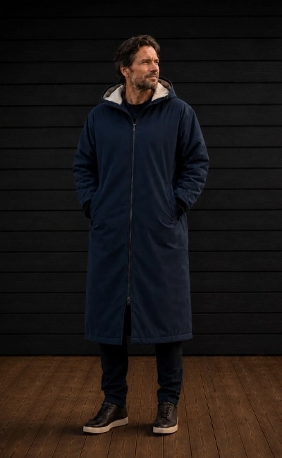 Mann med marineblå Comfyrobe foran en mørk trevegg.