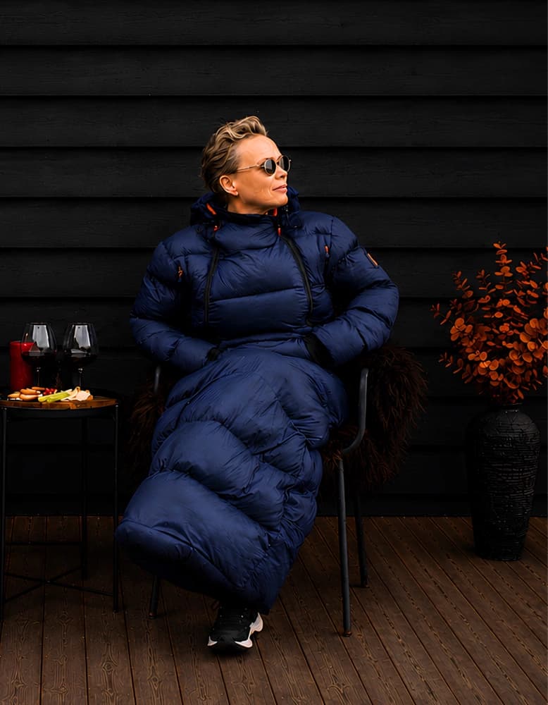 Person i mørkeblå Utekos TechDown™ sitter ved et lite utebord med servering.