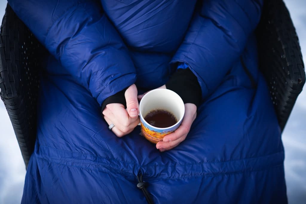 En person med en kaffekopp utenfor en bobil en kjølig høstmorgen.