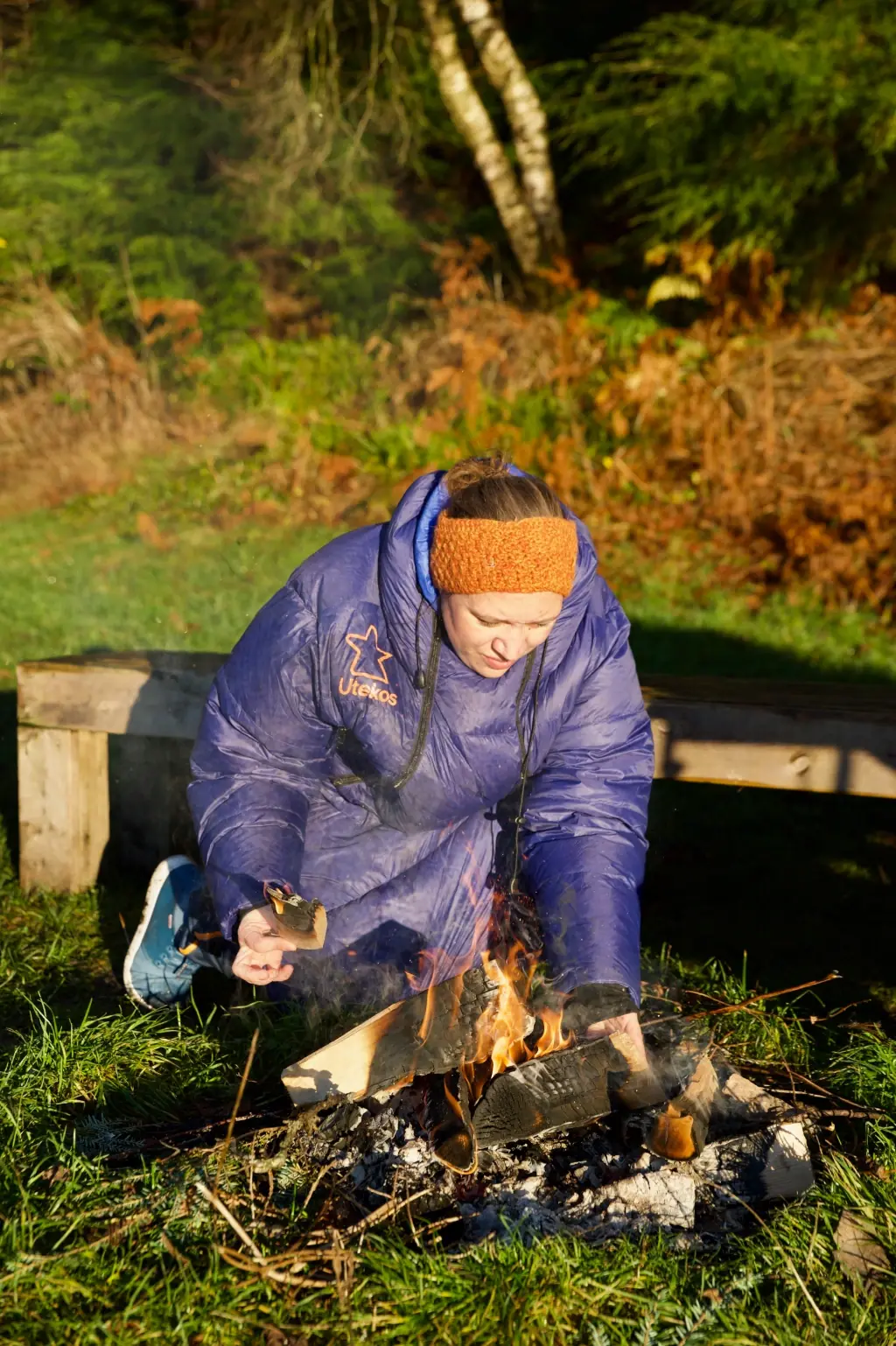 Et par sitter i campingstoler utenfor bobilen en kjølig kveld, begge kledd i Utekos.