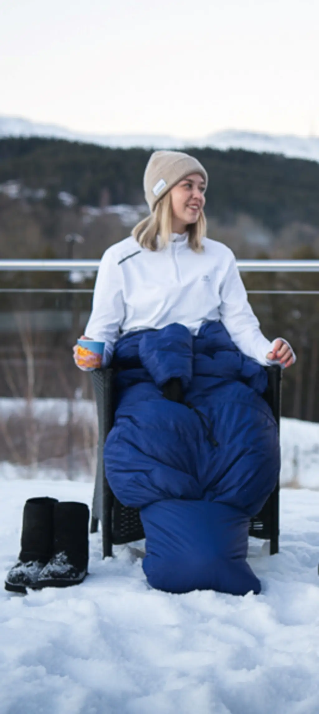 Person som slapper av med en bok i en campingstol, godt innpakket i Utekos.
