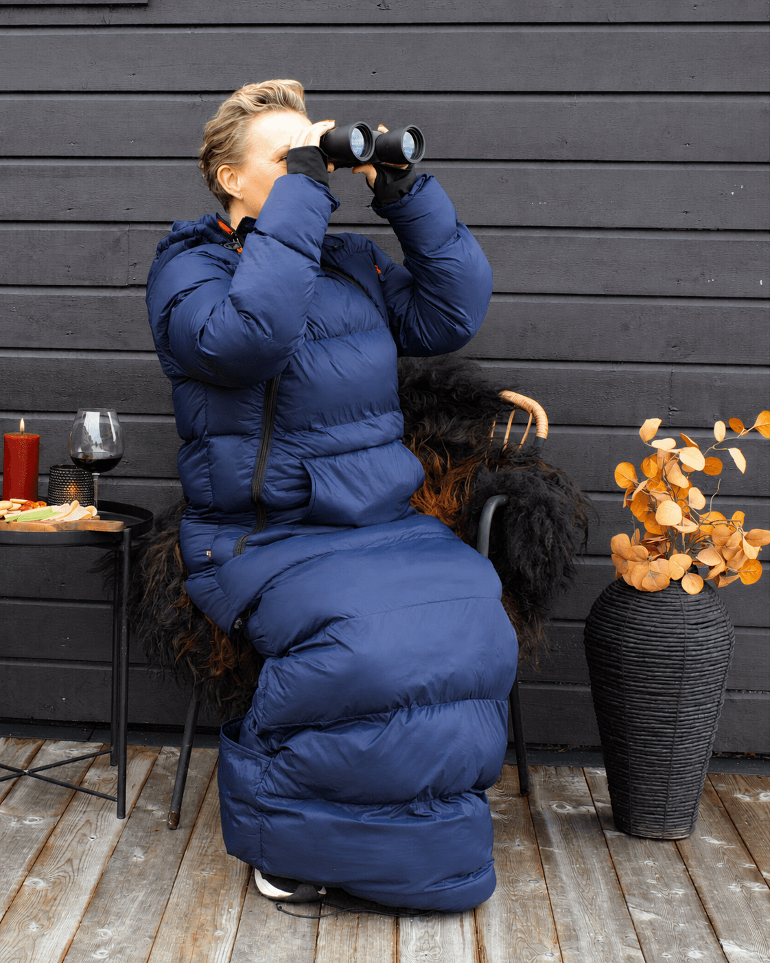 Kvinne med Utekos TechDown på terrasse ser på utsikt med kikkert.